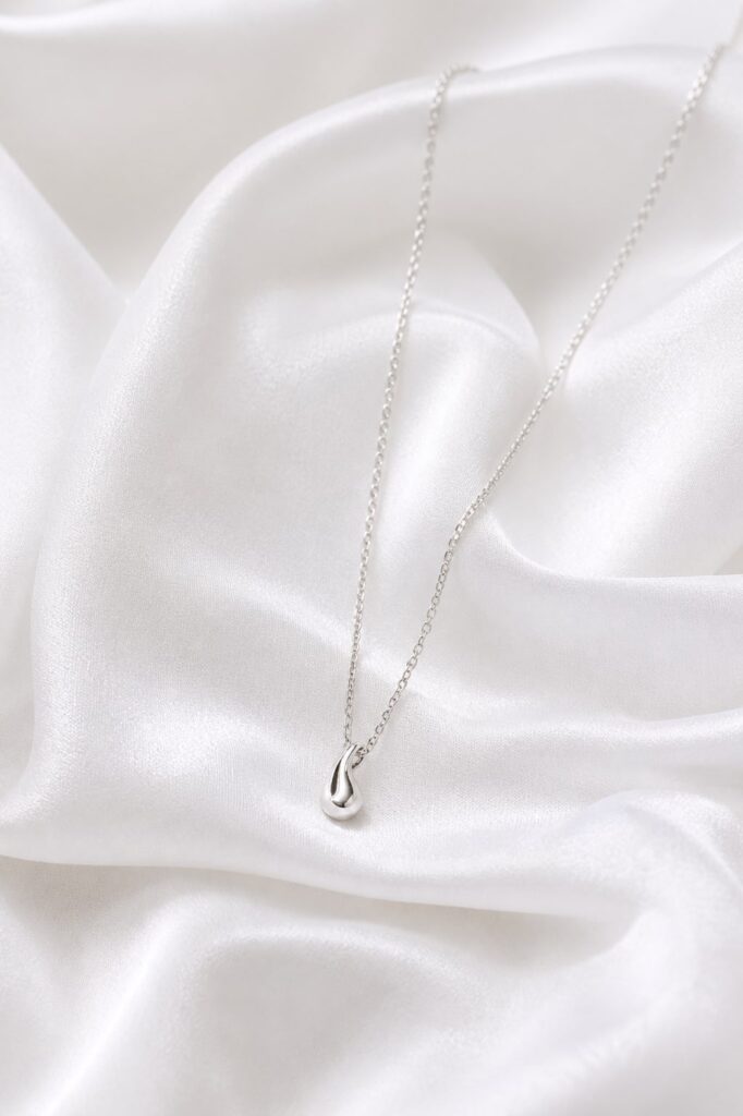 Delicate silver-tone layering necklace on white satin