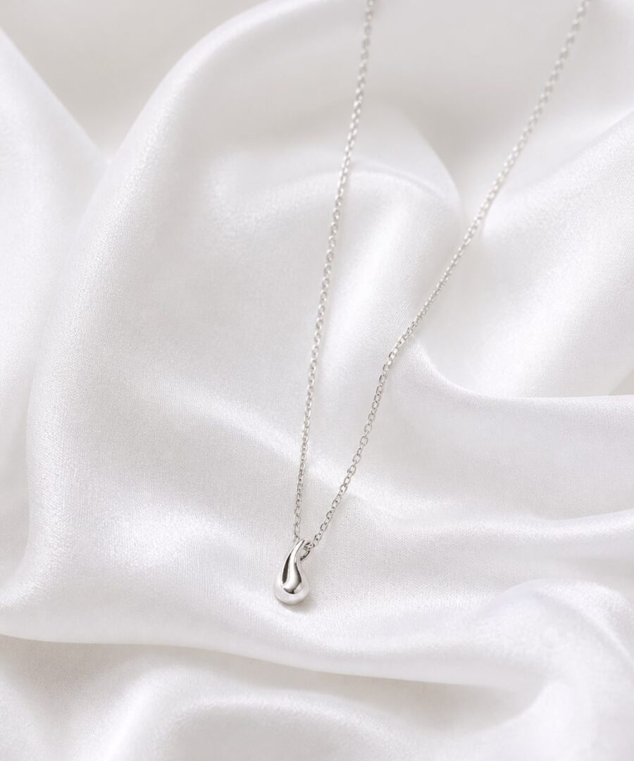 Delicate silver-tone layering necklace on white satin